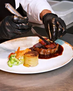 Chef emplatando un plato de carne con foie y guarnición en Le Gourmand Jávea